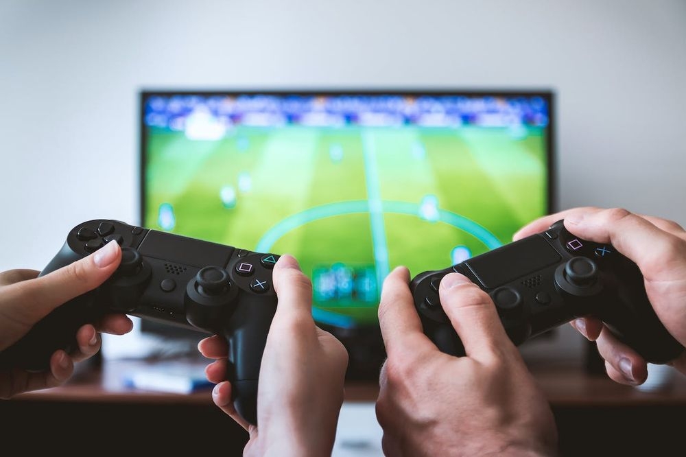controllers-in-foreground-football-game-on-tv